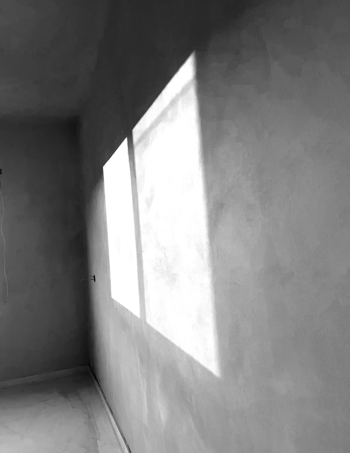 Hand-finished plaster wall with window light across it